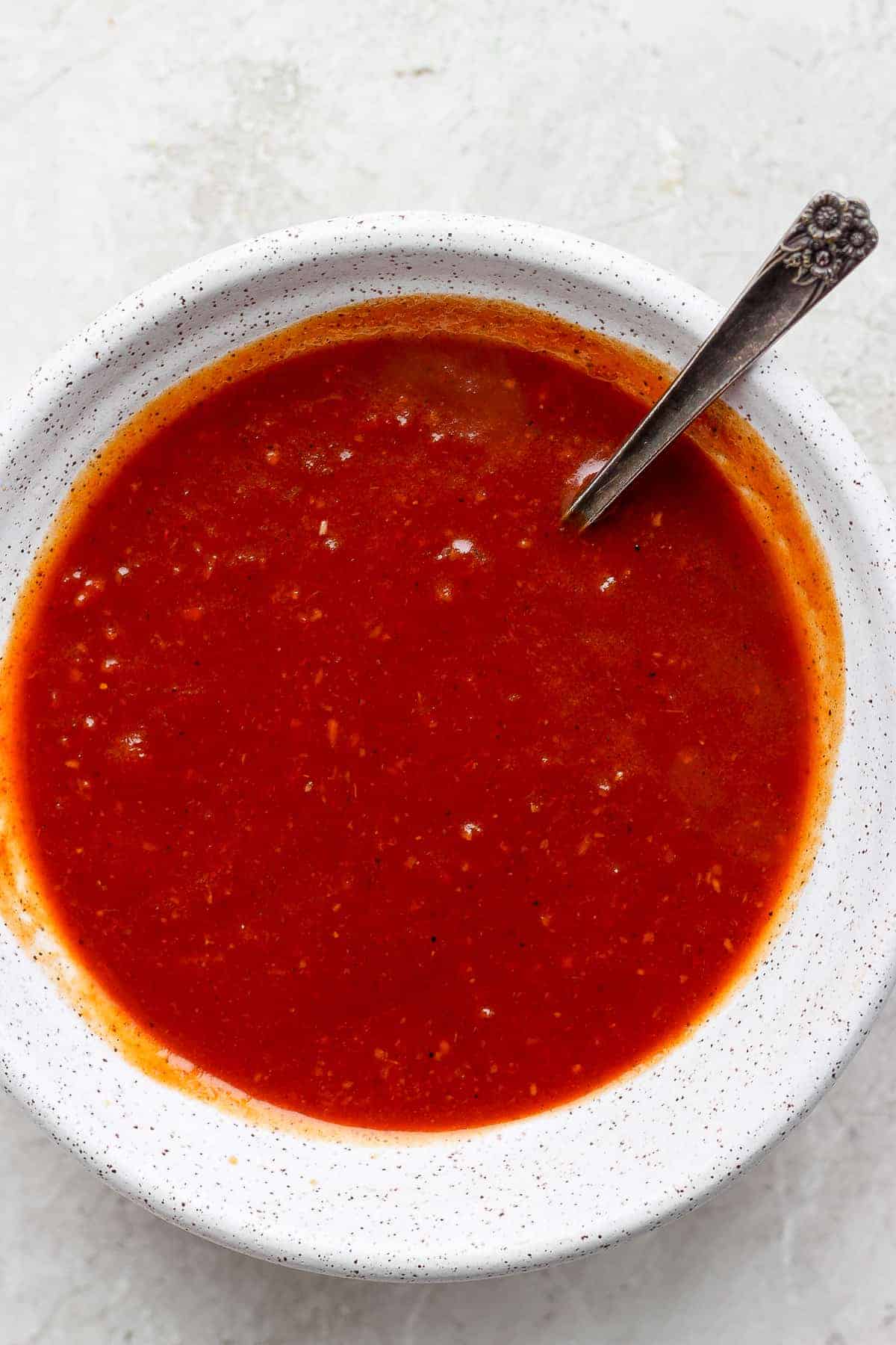 This Homemade BBQ Sauce is ready in under 30 minutes. No more store-bought BBQ filled with ingredients you can't pronounce. Make this BBQ sauce today! homemade BBQ sauce in a bowl with a spoon.