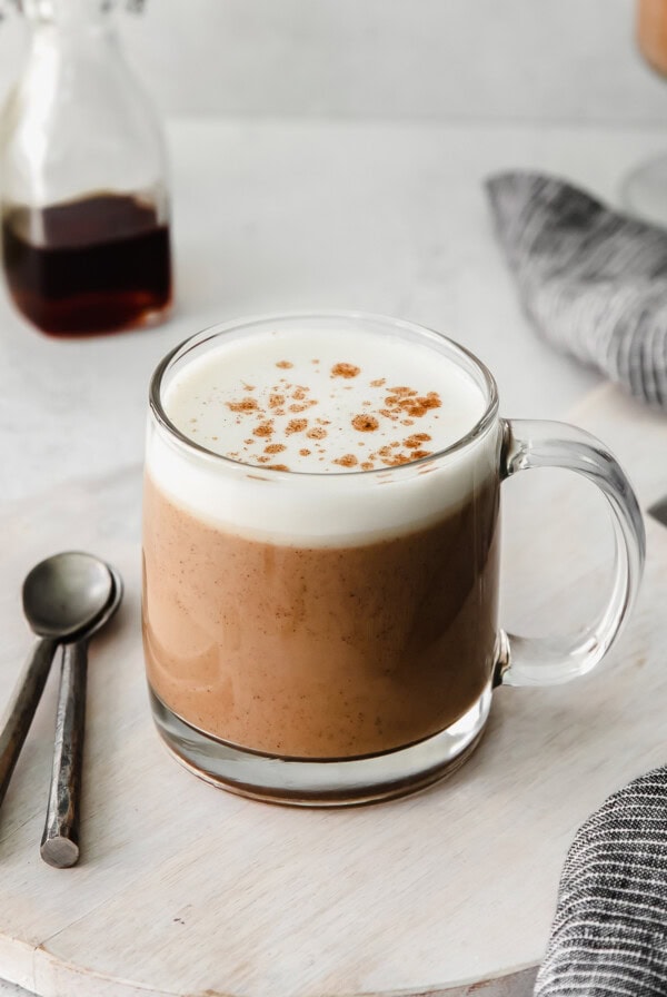A cup of chai tea latte with whipped cream and cinnamon.