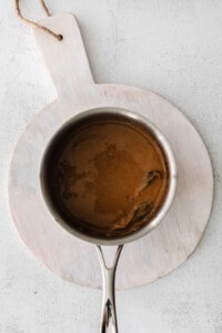 Brown sauce in a pan on a wooden cutting board.