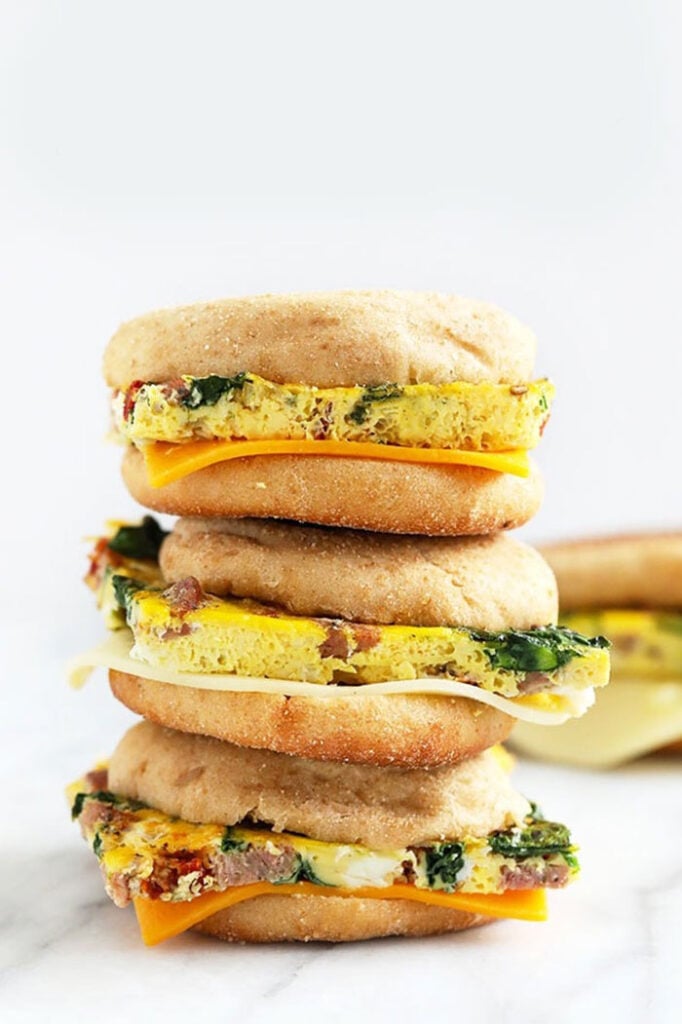 Need a quick grab-and-go breakfast? Make these delicious freezer breakfast sandwiches with homemade egg patties on an English muffin. freezer breakfast sandwiches stacked three high.