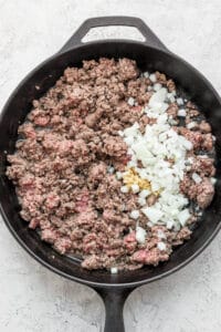 Ground beef and onions cooked in a skillet with flavorful slow cooker chili spices.