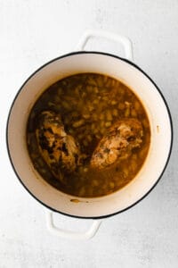 chicken and beans in a pot on a white background.