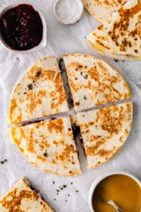Leftover Thanksgiving turkey quesadilla topped with cranberry chutney on a white plate.