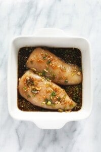 chicken marinating in dish.