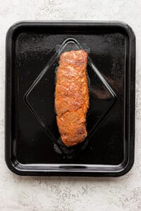 A piece of salmon cooked in an air fryer, served on a black tray.