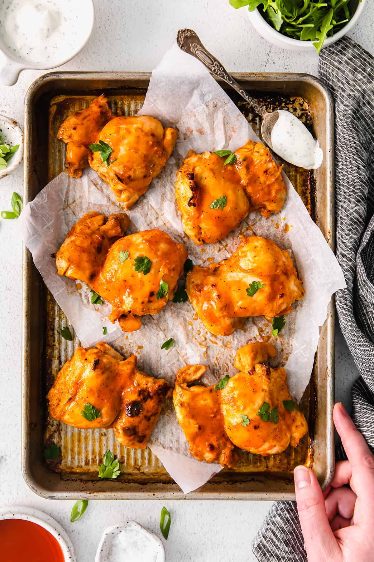 These incredibly juicy baked boneless chicken thighs are made in the oven with a homemade buffalo sauce. Enjoy! buffalo baked boneless chicken thighs on a baking sheet