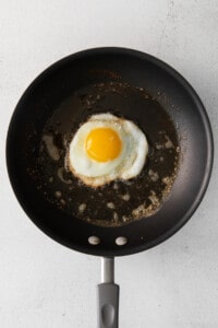 Et stekt egg i en stekepanne på en hvit bakgrunn.