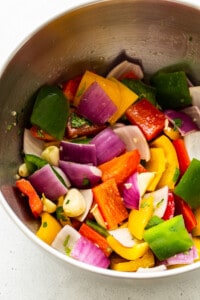 A bowl full of chopped peppers and onions.