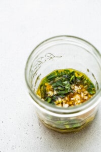 A glass jar filled with a mixture of herbs and spices.