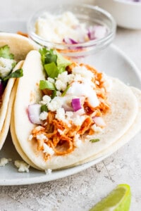 Chicken Tinga Tacos on a plate with toppings.