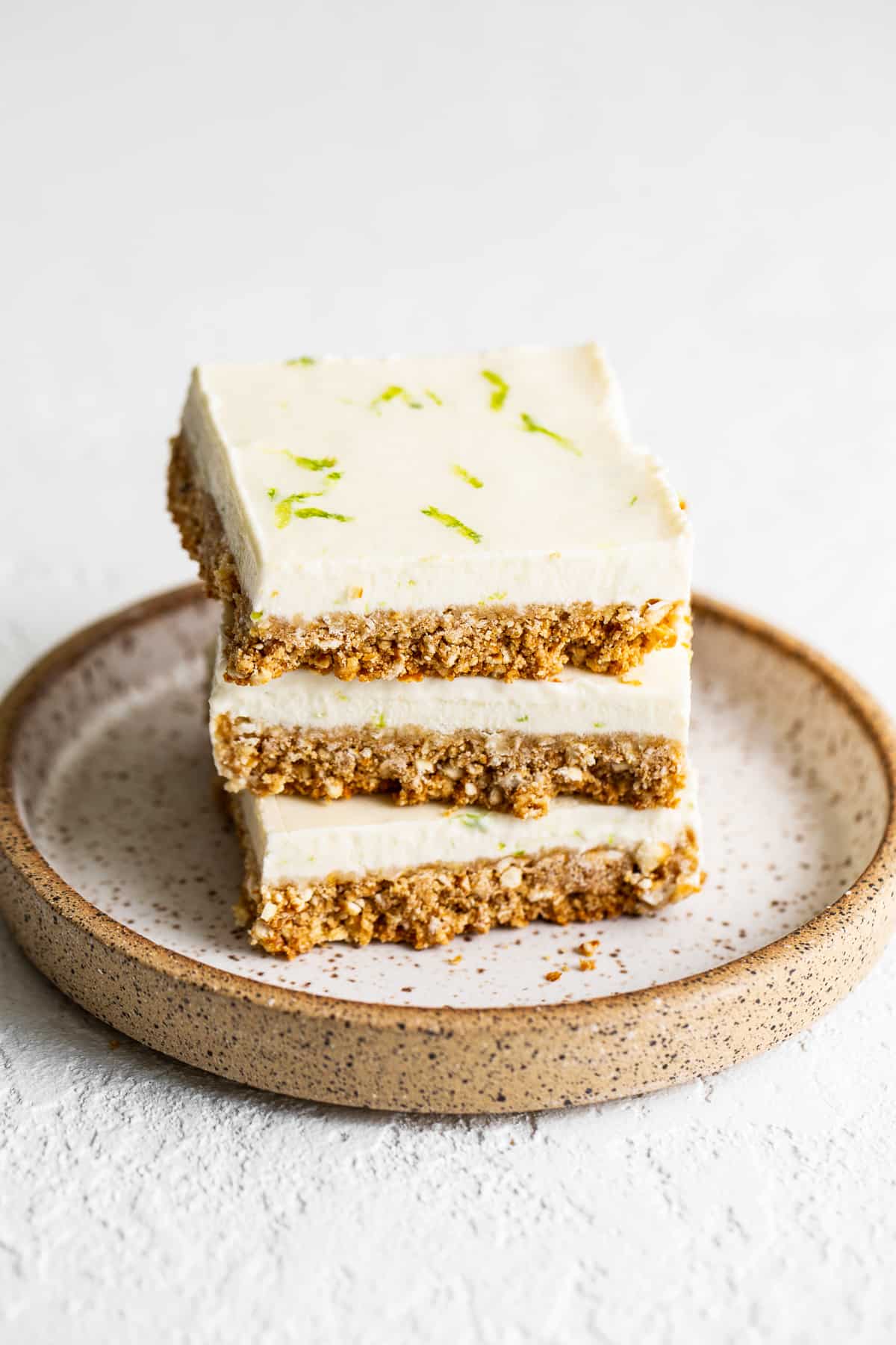 Margarita pie bars are an adult dessert made with a delicious salty crust and a creamy tequila-filled whipped topping. stack of margarita pie bars.