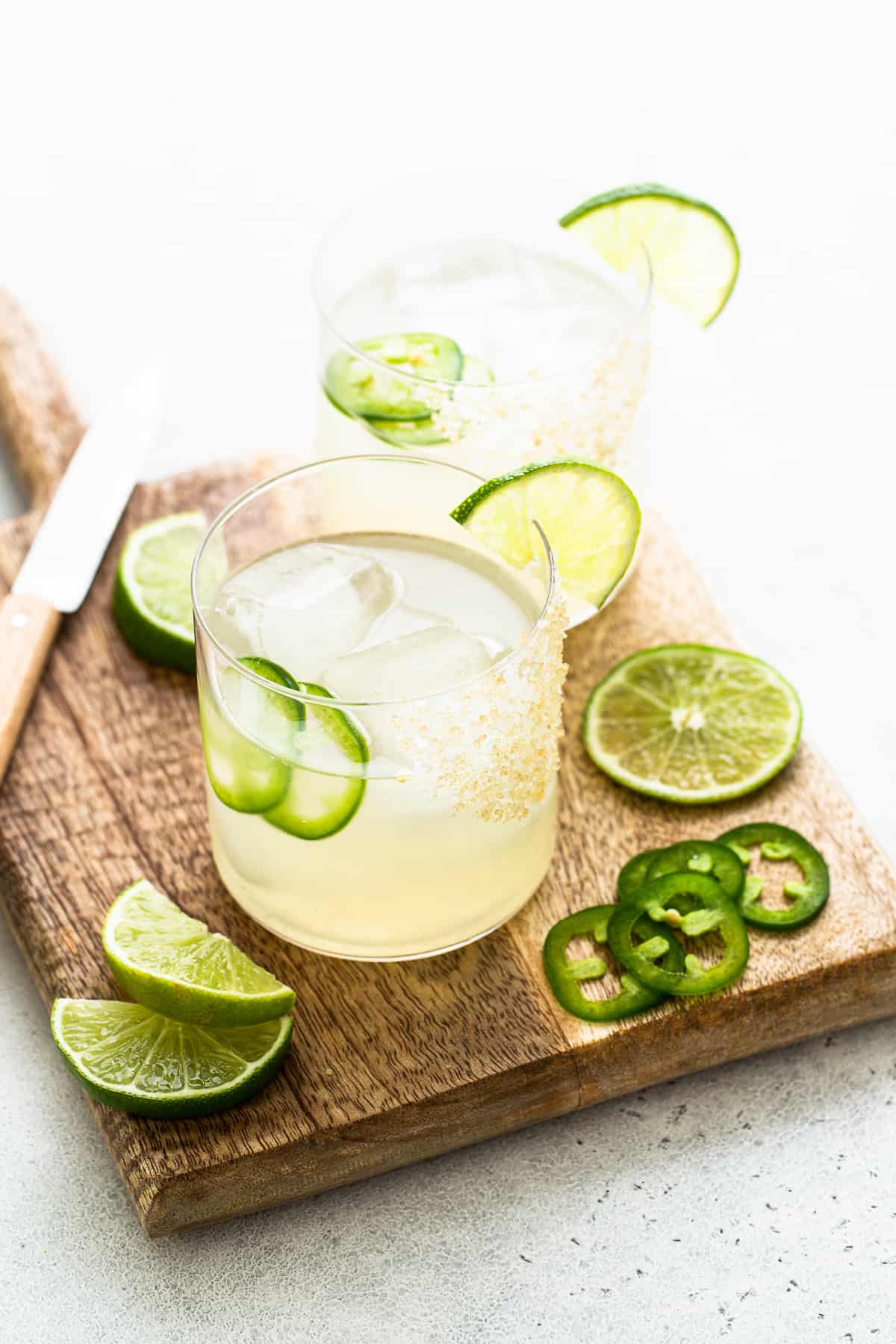 These spicy mezcal margaritas are made with high-quality mezcal, orange liquor, fresh lime juice, and a spicy agave simple syrup. Cheers! Spicy mezcal margaritas in a glass.