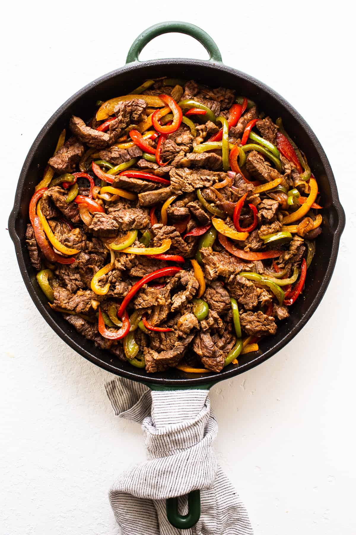 Steak fajitas and fajita veggies in a cast iron skillet.