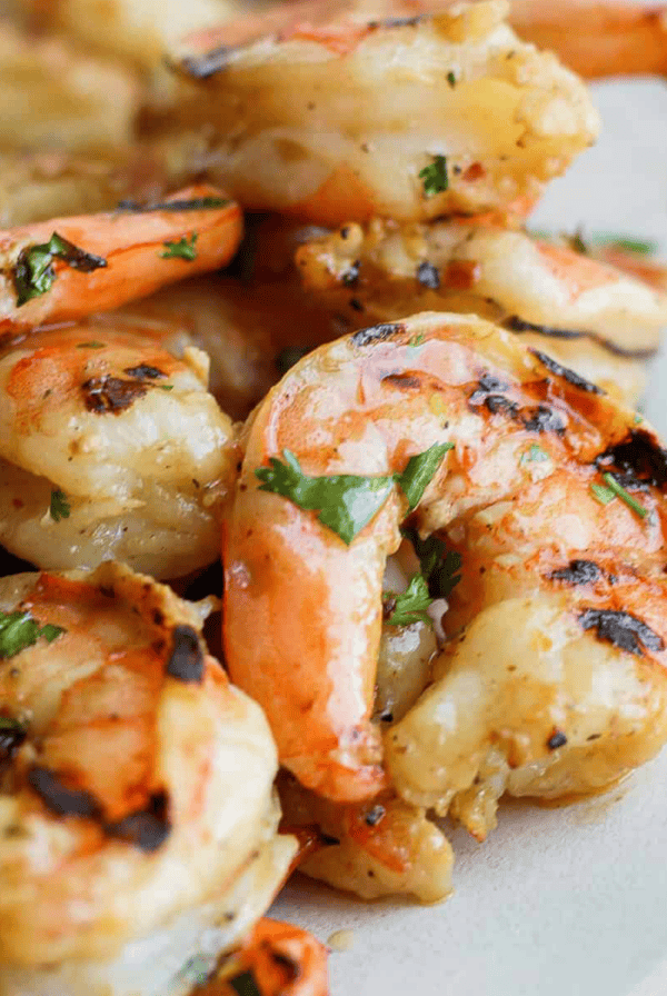 Grilled shrimp on a plate with lemon wedges, marinated.