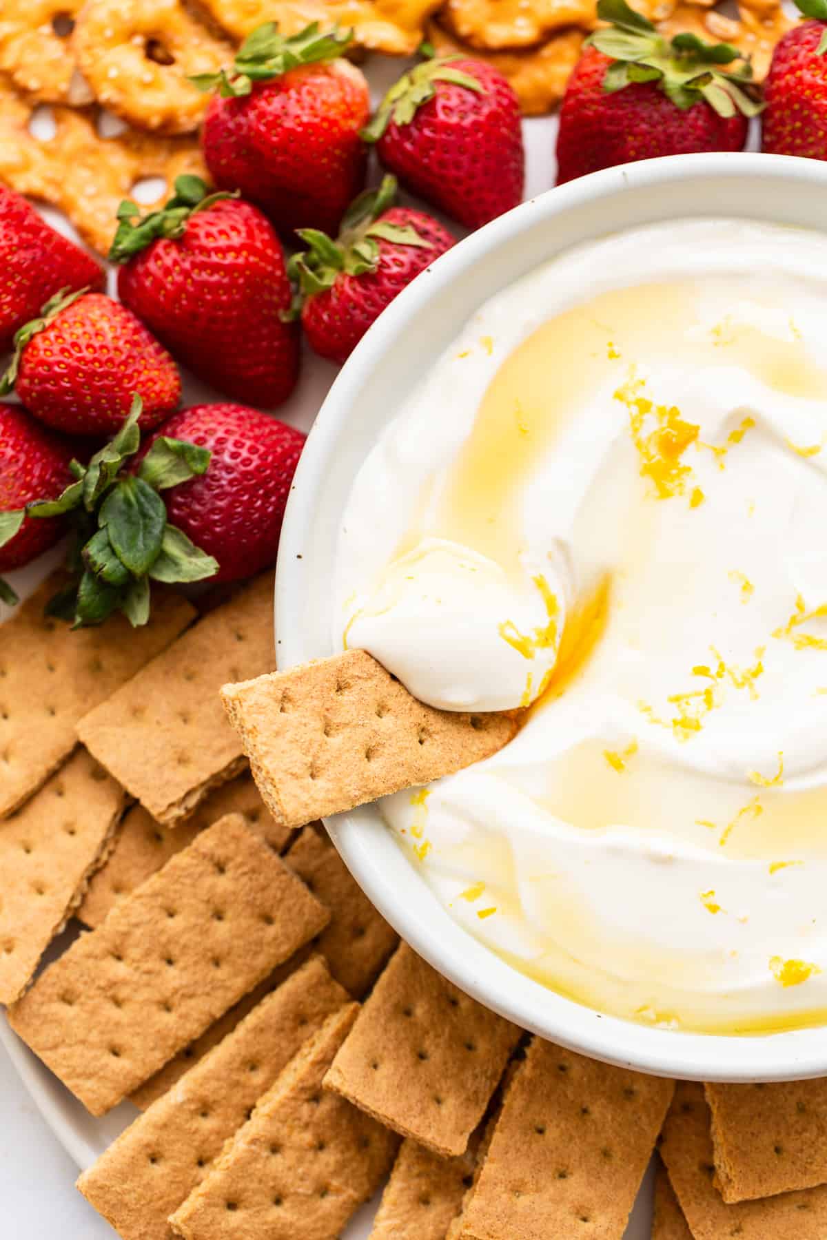 This Fruit Dip is the perfect dessert or sweet treat! Plus, it’s made with just 6 ingredients and is ready to enjoy in 10 minutes. Enjoy! Fruit dip surrounded by strawberries and graham crackers.
