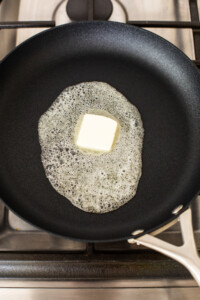 Butter in a frying pan on a stove.
