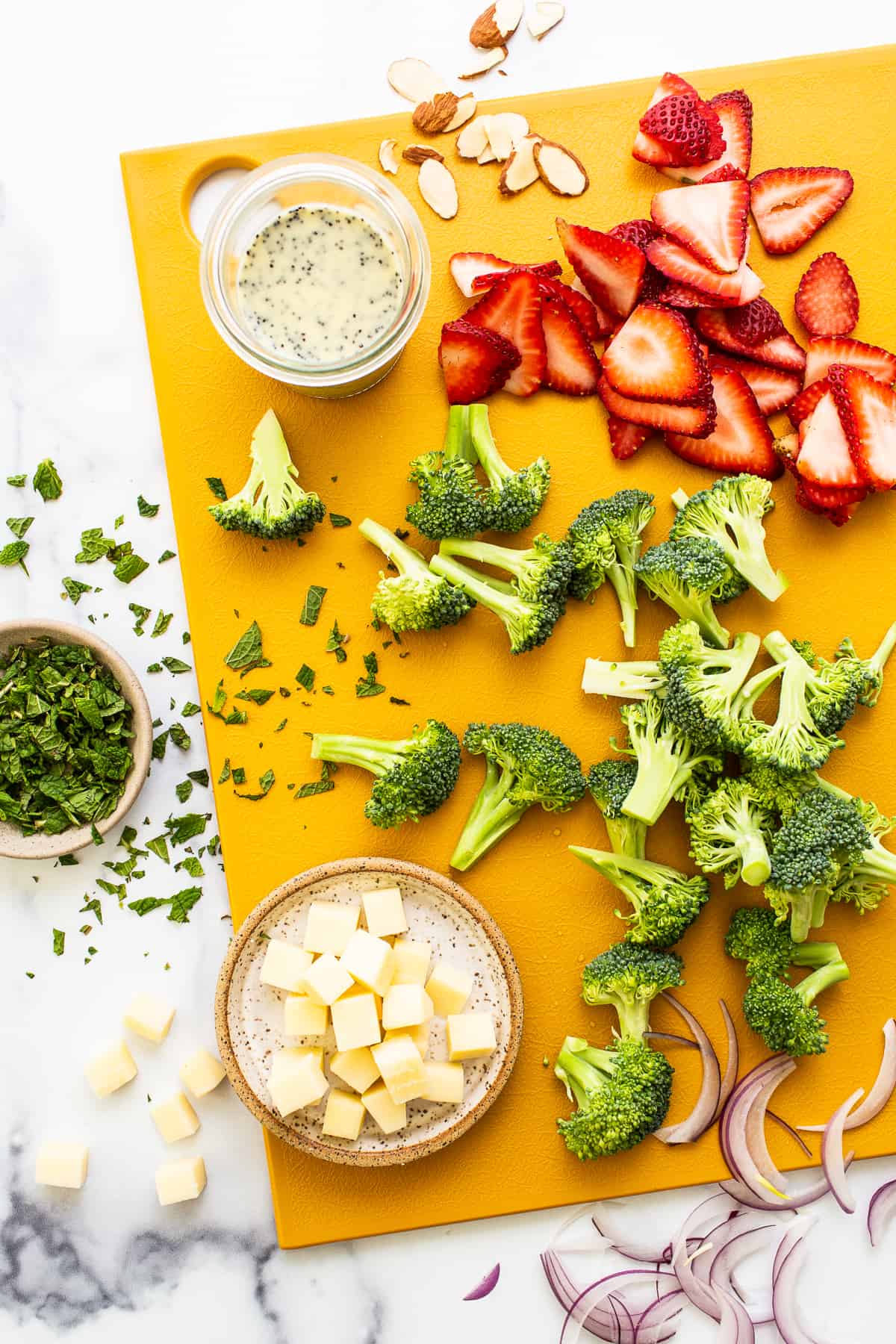 Ingredients for strawberry broccoli salad on a cutting board.