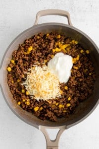 A skillet filled with beef, corn and sour cream.