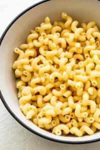 Macaroni in a bowl on a white surface.