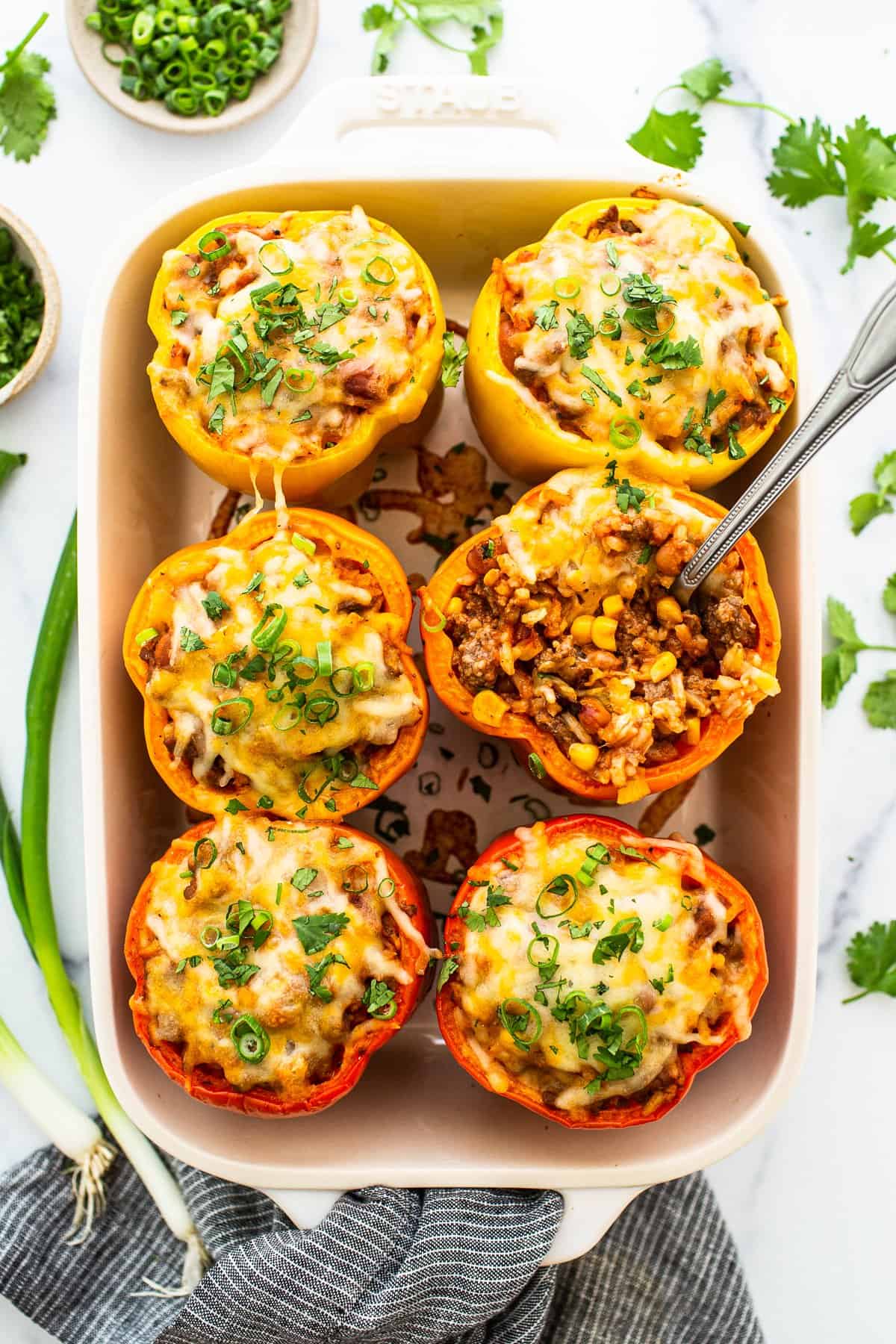 Easy stuffed peppers are a weeknight classic! Stuffed with ground beef, corn, rice and beans, seasoned with tomato sauce and classic spices, and then topped with cheese. Easy stuffed peppers in a casserole dish topped with shredded cheese.