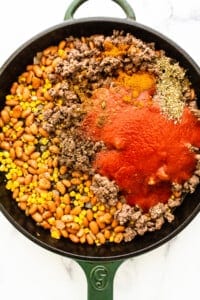 A skillet filled with ground beef, beans and tomatoes.