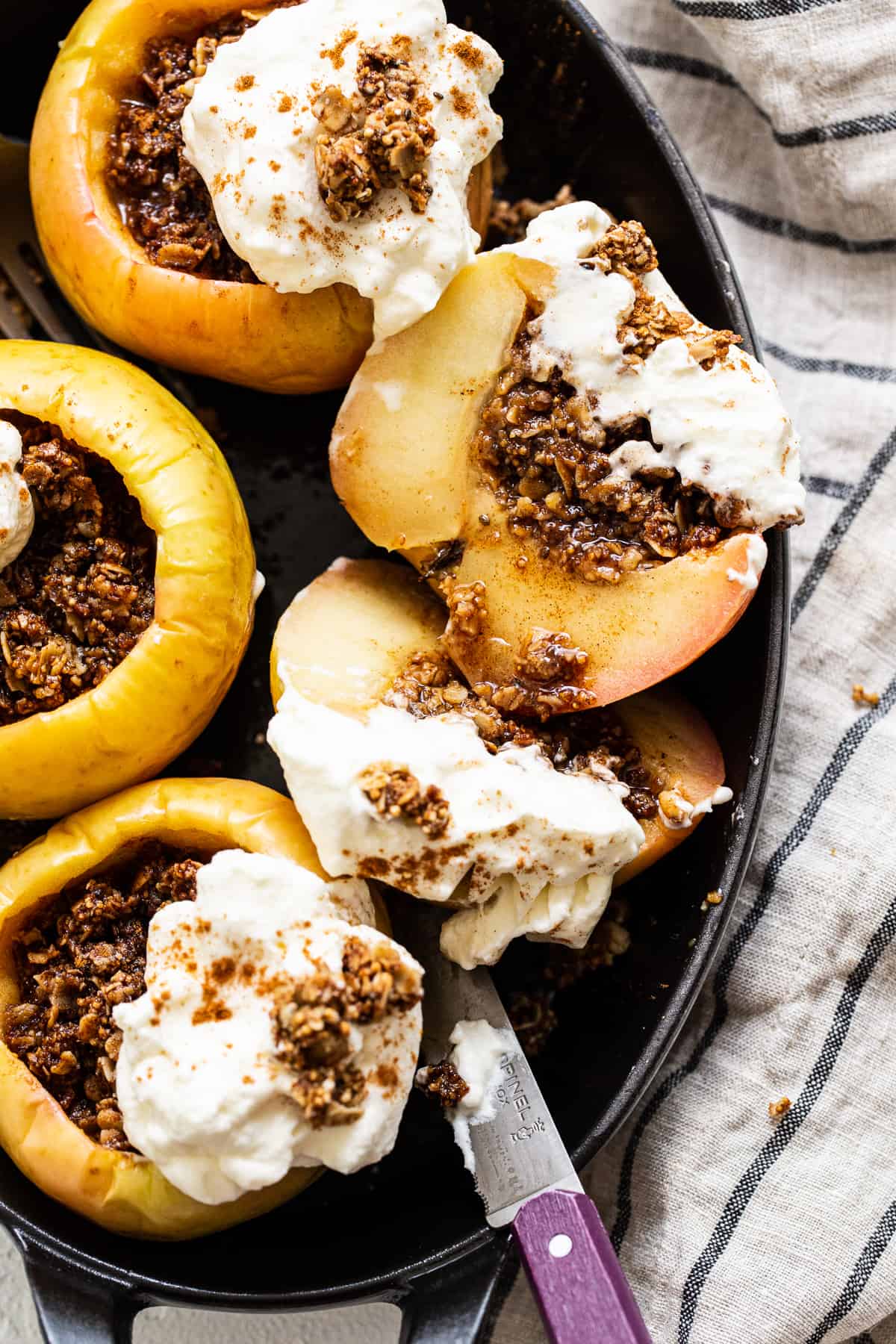 These easy baked apples are filled with a yummy granola streusel and baked to perfection. Top with ice cream or whipped cream for the ultimate fall dessert! Baked apples topped with whipped cream.