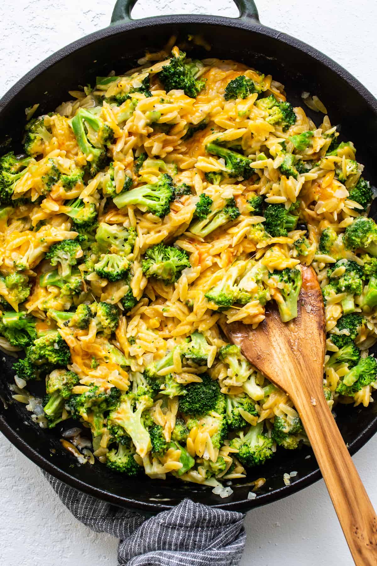 This broccoli cheese casserole is made in a cast iron skillet and features our favorite noodle - orzo! Cheesy broccoli casserole in skillet.