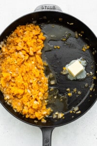 A frying pan with mashed sweet potatoes and butter.