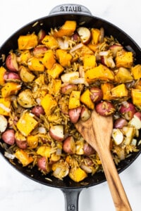 Butternut squash, red potatoes, and orzo in a skillet.