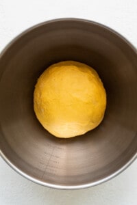 A ball of dough in a metal bowl.