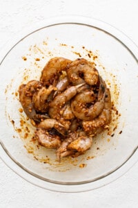 Shrimp in a glass bowl on a white surface.