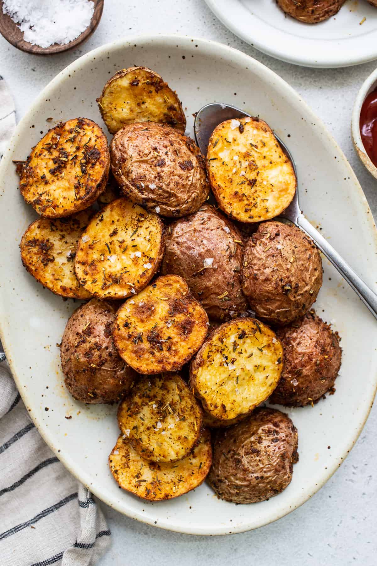 Make these crispy air fryer potatoes for perfectly crispy and seasoned skin and tender, fluffy potato on the inside! Crispy air fryer potatoes on a plate.