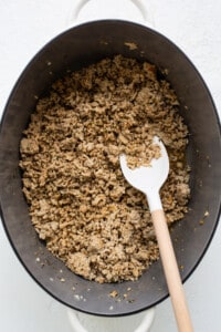 Granola in a pan with a wooden spoon.