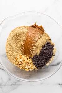 A glass bowl filled with ingredients for peanut butter granola.