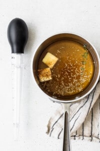 A pot of soup with a spoon and a measuring spoon.