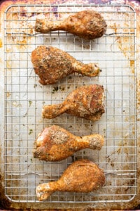 Roasted chicken legs on a cooling rack.