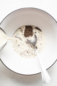 A spoon is pouring chia seeds into a bowl.