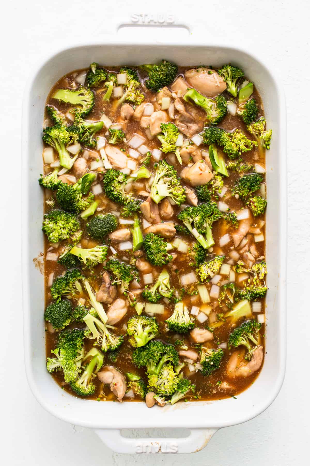 This Orange Chicken Casserole combines a classic takeout meal with easy at-home prep, made with just one dish! uncooked orange chicken casserole in dish.