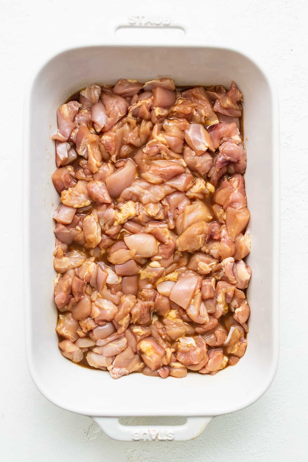 This Orange Chicken Casserole combines a classic takeout meal with easy at-home prep, made with just one dish! chicken marinating in casserole dish.