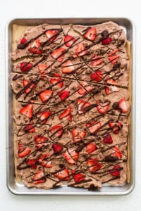A sheet of chocolate covered strawberries on a baking sheet.
