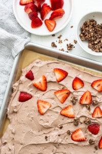 A sheet of chocolate cake with strawberries and graham cracker crumbs.