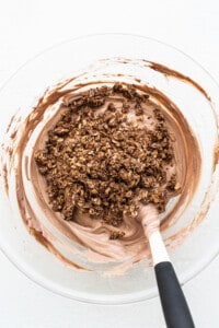 Chocolate granola in a bowl with a spatula.