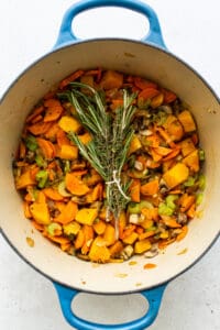 A pot filled with turkey, wild rice soup and sprigs of rosemary.
