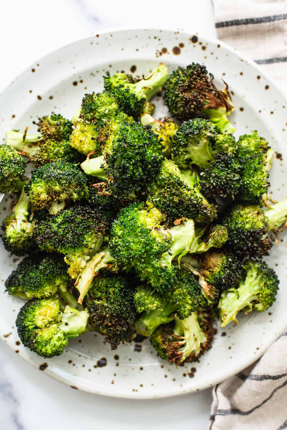 Air fryer broccoli is crisp, flavorful, and so easy to make. In less than 15 minutes, you'll have crispy air fryer broccoli ready to serve. Enjoy! Air fryer broccoli on a plate.