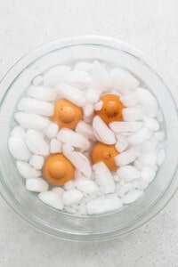 A glass bowl filled with eggs and ice cubes.