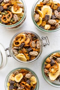 Four jars filled with nuts, seeds, and dried fruit.