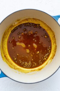 A pot with a sauce in it on a white surface.
