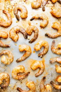 A baking sheet with shrimp on it.