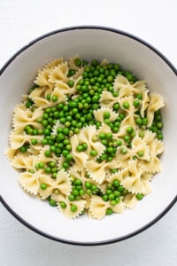 A bowl of pasta with peas in it.