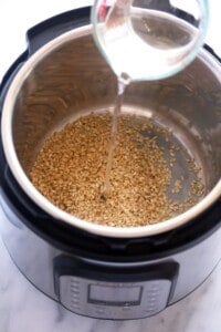 A liquid is being poured into a pot of grains.